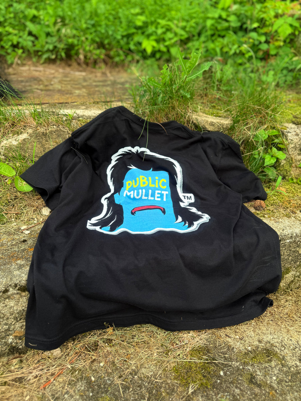 PUBLIC MULLET: FIRST RUN — physical shirt laid flat showing the softer faded print